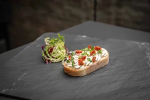 Belegtes Brötchen mit aufgeschlagenem Frischkäse und getrockneten Tomaten