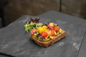 Offener dunkler Toast mit Avocado-Guacamole und Kirschtomaten